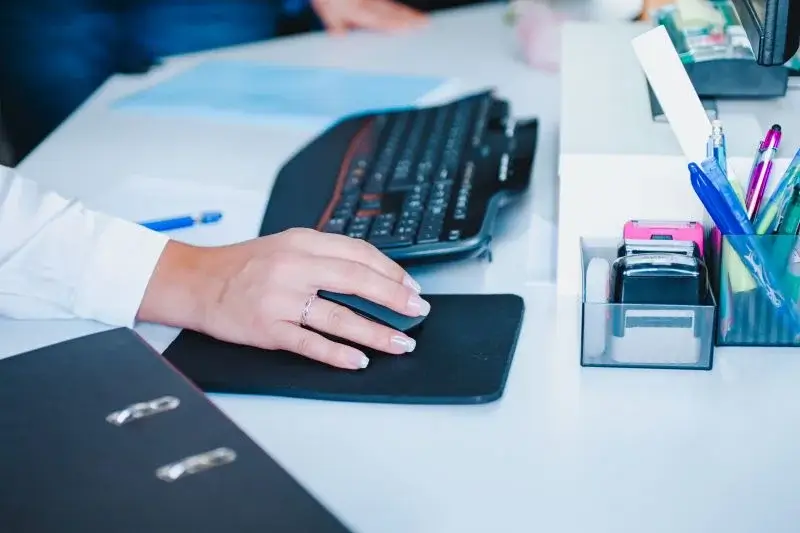 Hand auf einer Computermaus im Büro